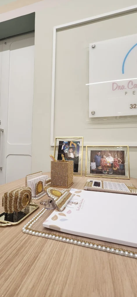 Detalhes decorativos com pérolas e logotipo da Dra. Camila